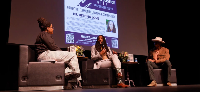 Three people seated on the stage in a forum discussion