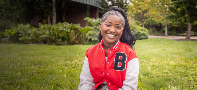 Ballard High School graduate smiling with red and black letterman jacket