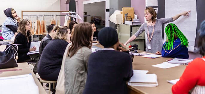 faculty member pointing to a blackboard in an apparel design class with students