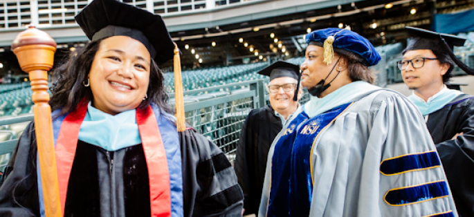 Chancellor Rosie Rimando-Chareunsap holding the academic mace with other college officials at commencement