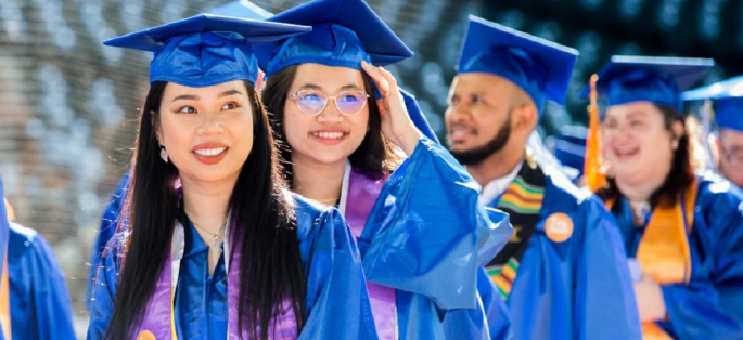 students in line wearing caps and gowns preparing to cross the stage