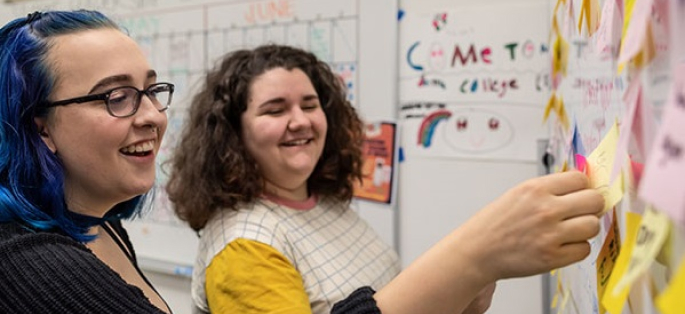 two students in a class at an info board