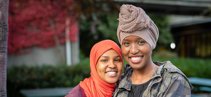 two smiling students wearing traditional head coverings