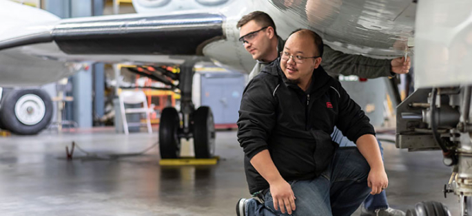 South Seattle College students in aviation class under a plane wing