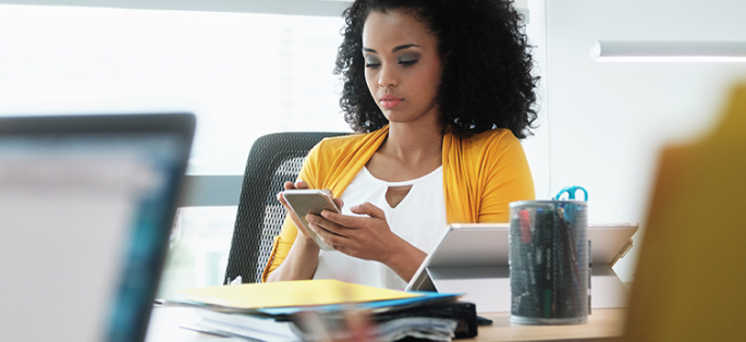 Woman sitting at conference table looking at phone