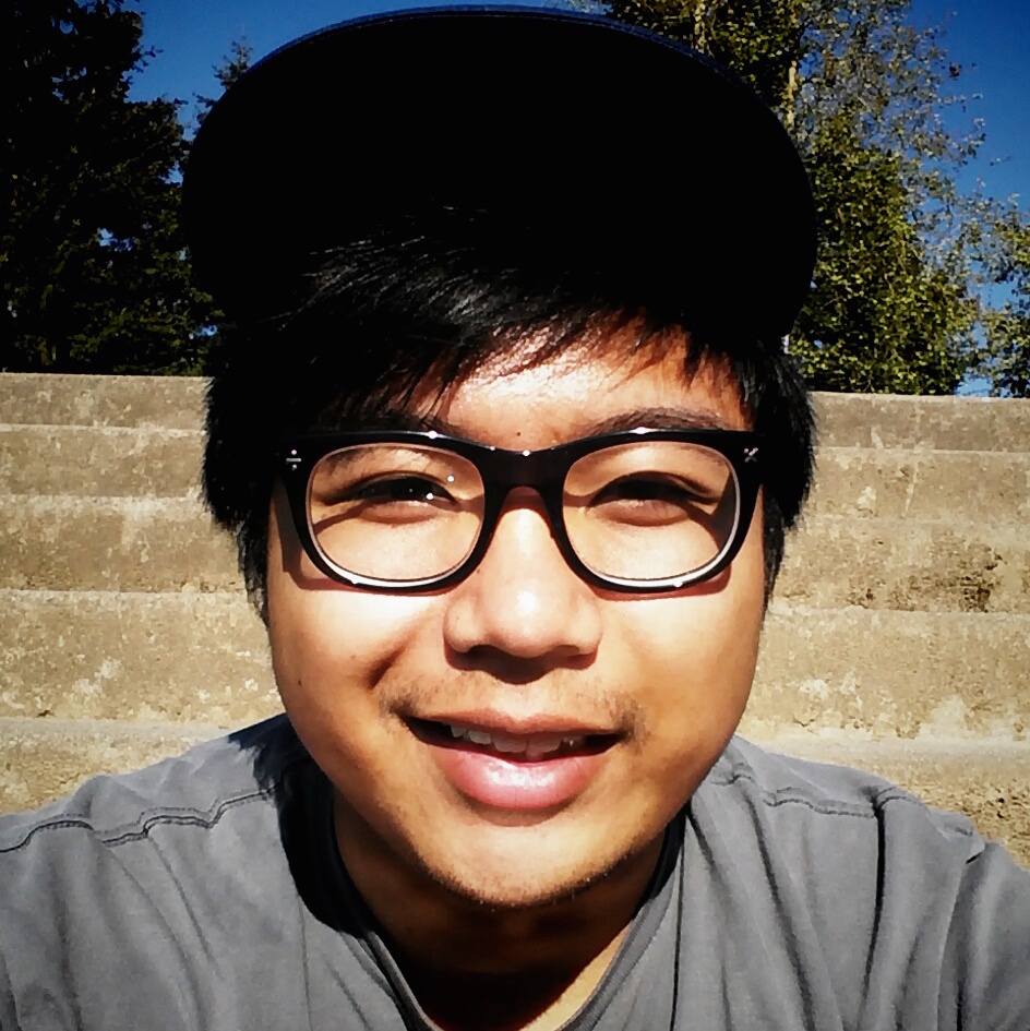 Close up of Spencer outside with steps behind him, wearing glasses and and hat, looking directly into the camera.